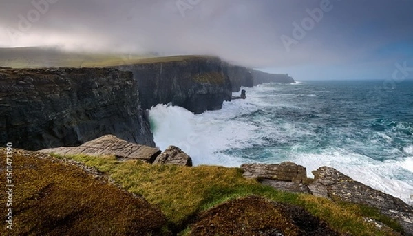 Fototapeta dramatic coastal cliffs with crashing waves under a misty sky showcasing nature s power and beauty