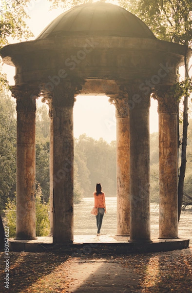 Fototapeta A Woman Stands Alone In A Rotunda In A Park On A Sunny Cozy Romantic Atmosphere