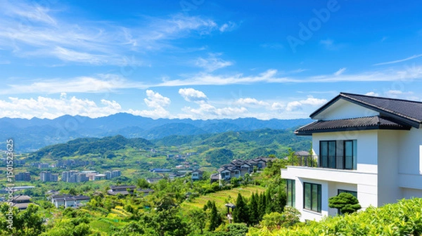 Fototapeta Beautiful two story villa overlooking lush green landscape with mountains in background, showcasing serene and tranquil environment