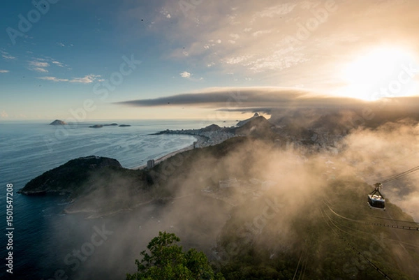 Fototapeta Famous View of Rio de Janeiro Coast from the Sugarloaf Mountain Under Clouds on Sunset and Cable Car Approaching