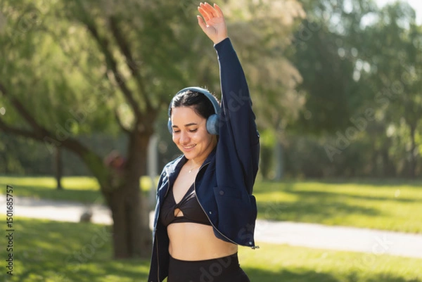 Fototapeta A woman performs exercise and shoulder and arm stretches in the park in the morning