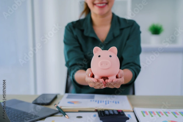 Obraz Young beautiful asian woman sitting at table and looking at growing stack of coins, financial debt employee bonus concept.