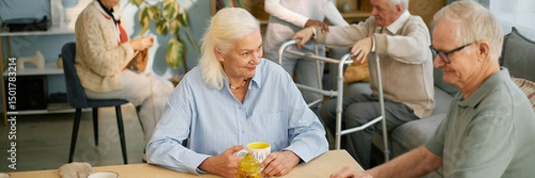Fototapeta Elderly people engaged in conversation and activities in communal area of nursing home, showing warm interactions and caregiver assistance