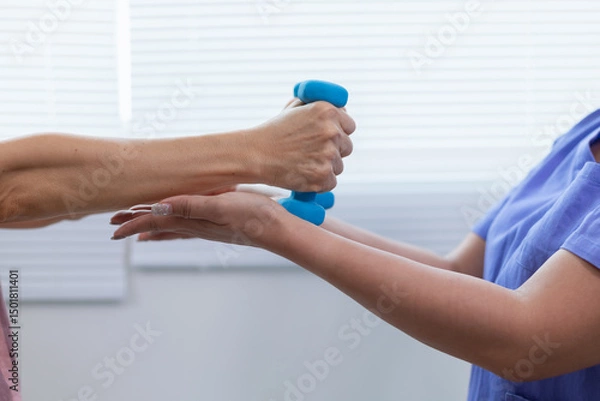 Obraz A female doctor is giving an elderly person dumbbells for exercise or physical therapy to make the muscles work and physical therapy also helps to restore the body to work at its full potential.
