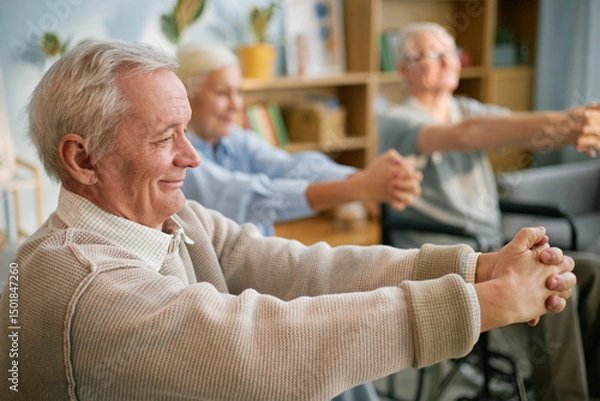 Fototapeta Elderly people in retirement home performing stretching exercises while seated, focusing on health and well-being amid light-filled indoor setting with plants and bookshelves