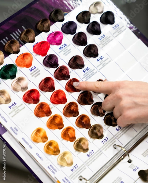 Fototapeta A woman client points to a hair color on a palette with hair dye samples. Close-up. Selective focus.