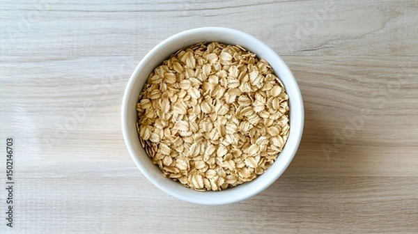 Fototapeta Bowl of Rolled Oats on Wooden Surface