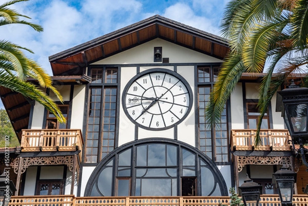 Fototapeta A large restaurant in Gagra. The building is decorated with a large clock visible from afar. This unusual restaurant building with a clock was brought from Scandinavia