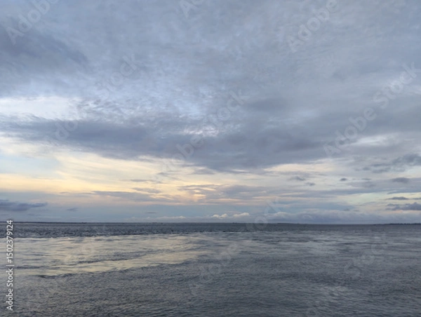 Fototapeta Front view of waves at empty beach and cloudy grey sky