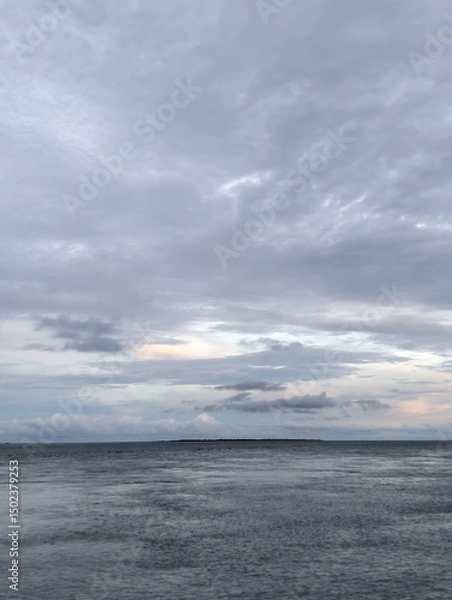 Fototapeta The sky is cloudy and the ocean is calm, Calm ocean waves rolling onto sandy beach under cloudy sky scenic view from above nature landscape seascape coastal scene
