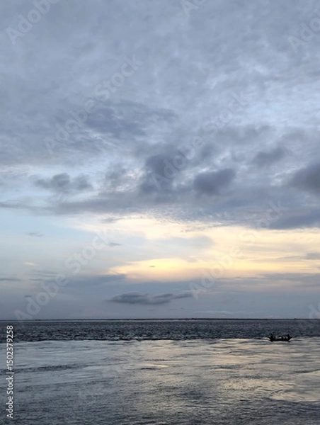 Fototapeta A beach with a cloudy sky in the background