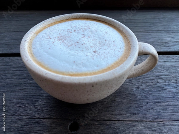 Obraz Hot cappuccino coffee in white cup on wooden table background. Art of milk foam circle shape with copy space on brown melt coffee top view