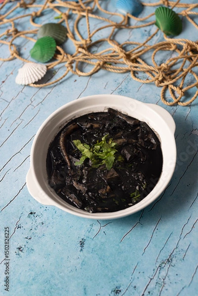 Fototapeta Squid in rich black ink sauce garnished with fresh parsley.