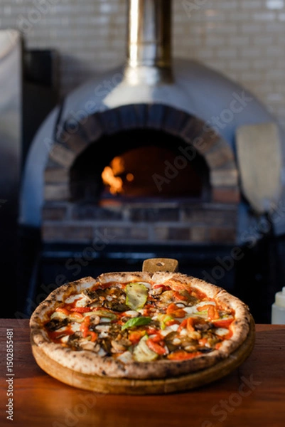 Fototapeta Rustic vegetable pizza served on checkered cloth in outdoor setting.