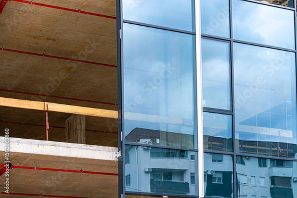 Fototapeta Installation of unitized glass curtain wall panel on modern concrete building under construction