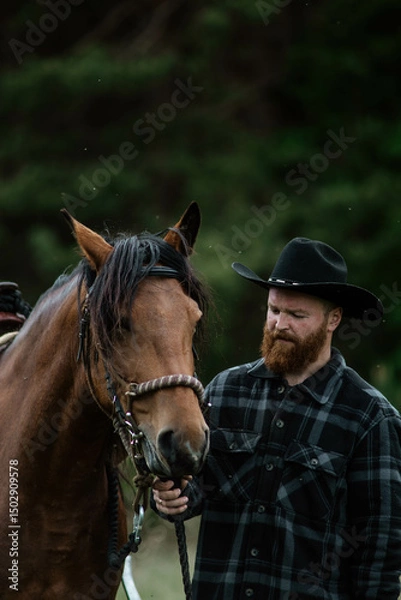 Fototapeta cowboy man with red beard in hat with horse close-up, friendship with animal