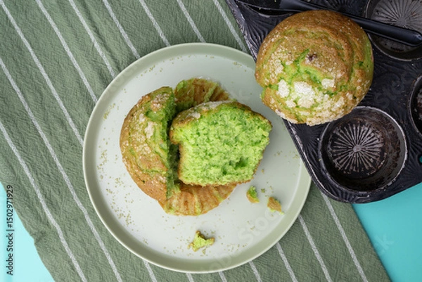 Obraz Matcha green tea muffin, sliced in half, on a pale green plate with a green and white striped towel.