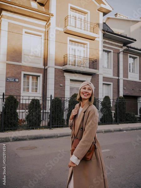 Obraz Beautiful young woman in coat walking around european city