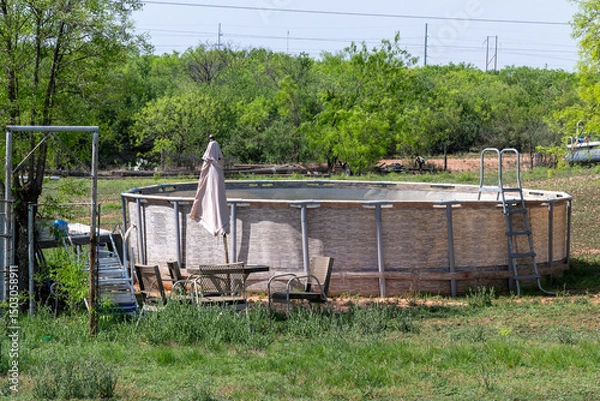 Fototapeta An empty swimming pool and a patio set in a Texas ranch