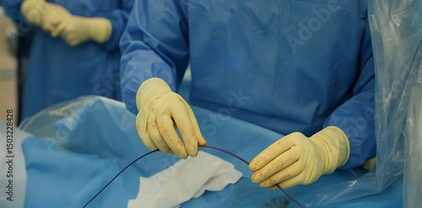 Fototapeta Interventional radiologist performing minimally invasive procedure with precision microcatheter in sterile medical environment