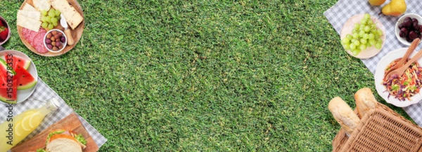 Obraz Summer picnic food double border. Top view with blanket over a green lawn banner background. Picnic basket, fruit, salad, sandwiches and snacks. Copy space.