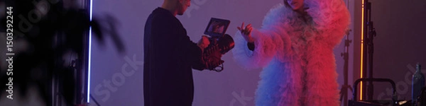 Fototapeta Header image of studio filming setup with woman performing in costume and cameraman recording during video shoot