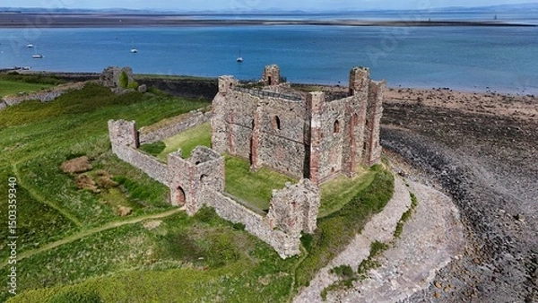 Fototapeta Drone view of medieval castle ruins overlooking the sea with boats and coastline