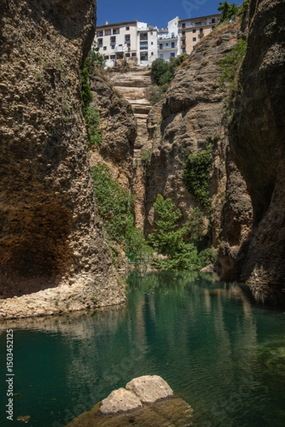 Fototapeta View from Water Mine in Ronda. Below View of Green River, Steep Cliffs and Buildings on Rock in Spain.