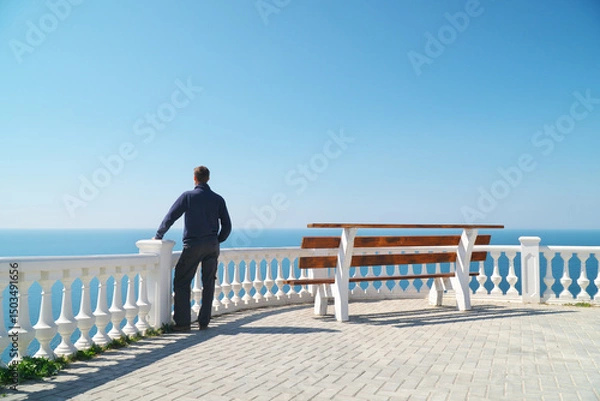 Obraz Man standing on balcony and look on the sea horizon at day.