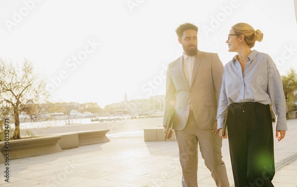 Obraz In an Urban Setting, a Professional Couple is Walking at Sunset, Enjoying Togetherness