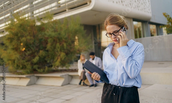 Obraz A professional woman on a phone call in a modern urban setting, highlighting career aspects