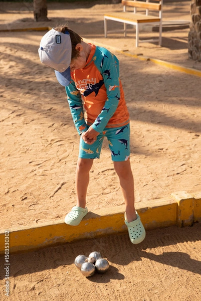 Fototapeta Man and boy playing petanque in hot country, father and son in hotel playing on sand