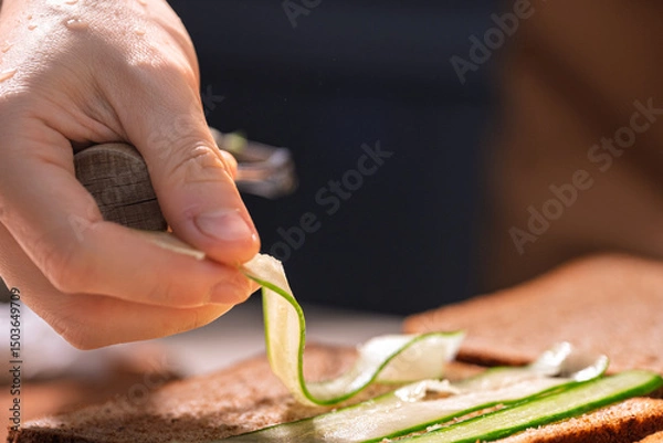 Fototapeta Hand Slicing Cucumber with a Knife Blade