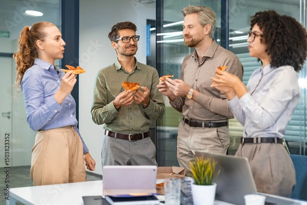 Fototapeta Happy multiracial colleagues have fun at lunch break in office. Excited workers celebrate shared win ordering takeaway pizza