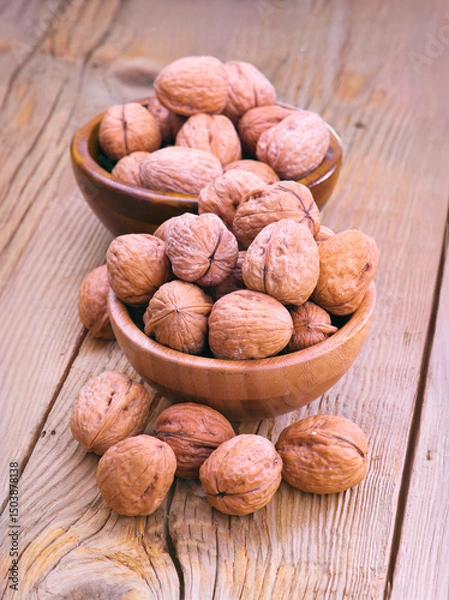 Fototapeta Walnuts filling two wooden bowls resting on rustic table