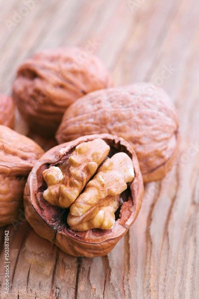 Fototapeta Walnuts cracked open on rustic wooden table displaying nutritious seed