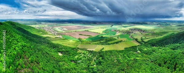 Obraz Storm rainy clouds above a village and green mountain and field landscape - panorama of Slovakia