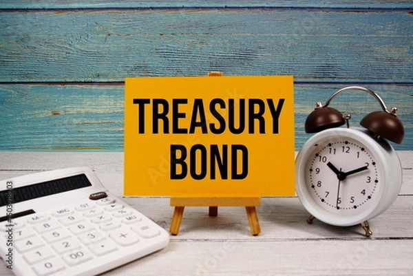 Fototapeta Treasury Bond text written on paper card with calculator and alarm clock on wooden background