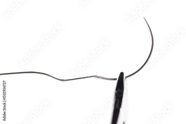 Fototapeta Close-up of a surgical needle threaded with non-absorbable suture. Sharp point and fine thread against a white background.