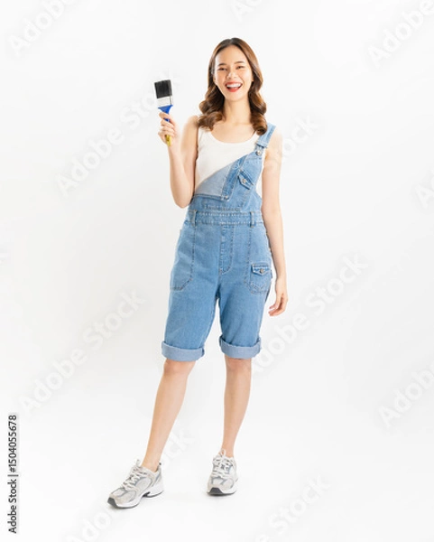 Fototapeta Appealing Asian woman holds paintbrushes on white background.