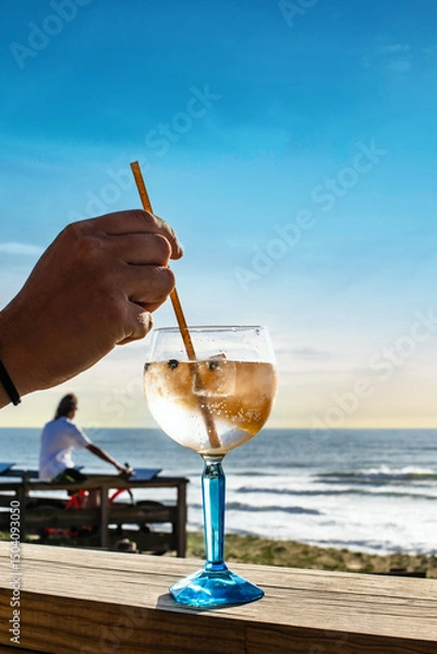 Obraz Young woman drinking a gin and tonic on a terrace. facing the ocean
