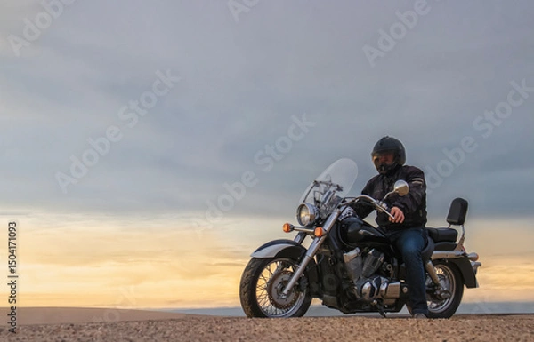 Fototapeta Real photo of a man on motorcycle in desert during sunset with dramatic clouds — concept of freedom, travel, solitude, adventure, and outdoor lifestyle in wild open landscapes