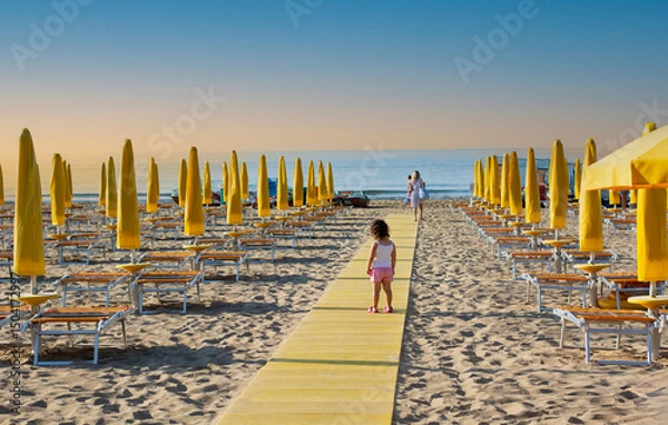 Obraz a little girl walks towards her mother on a beach walkway
