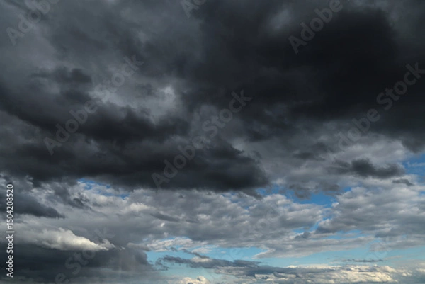 Obraz Epic Dramatic storm dark grey black cumulus rain clouds against blue sky background texture, thunderstorm
