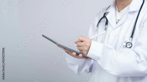 Fototapeta A healthcare professional in a white coat is using a tablet, symbolizing modern medicine and digital health technology.