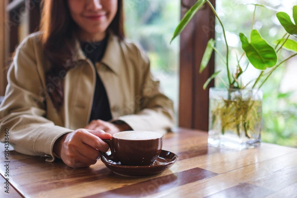 Fototapeta Closeup image of a woman holding a cup of hot coffee in cafe
