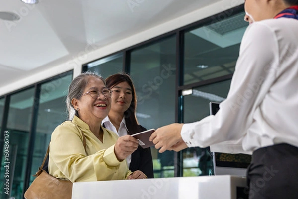 Fototapeta Asian senior passenger is showing their boarding pass to the airline ground crew at departure gate into the airplane for final inspection before boarding into plane