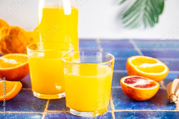 Fototapeta Fresh orange juice on table with slices fruits.