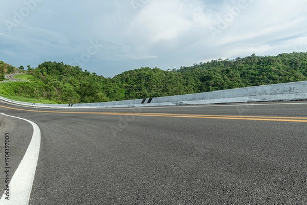 Fototapeta Long curvy forest asphalt road over the hills. Side view of road with beautiful mountains, Road background.