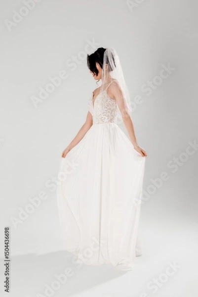 Fototapeta Bride in elegant white dress posing gracefully in a studio setting during a fashion shoot